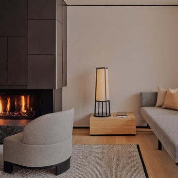 Junior Suite at Aman Rosa Alpina with fireplace, curved seating, and modern wood heater.