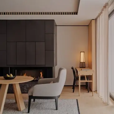 Deluxe bedroom with desk, chair and fireplace at Aman Rosa Alpina resort.