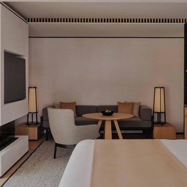 Deluxe Suite at Aman Rosa Alpina with seating area, fireplace and modern furnishings in neutral tones.