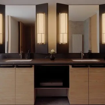 Principal bedroom ensuite at Aman Rosa Alpina resort with dual vanities and illuminated mirror panels.