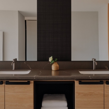 Bathroom at Aman Rosa Alpina with dual vanity, black-framed mirror and wooden cabinetry.