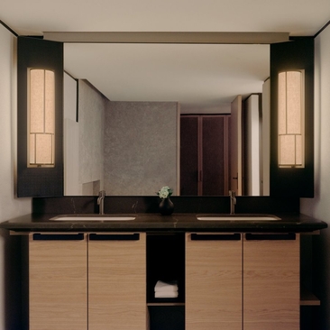 Superior room bathroom at Aman Rosa Alpina with dual vanity, illuminated mirrors and natural wood cabinetry.