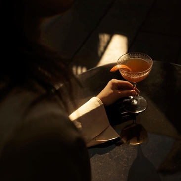 アマン ニューヨークのコーナーバーで、夕暮れ時の光に照らされたカクテルグラス。