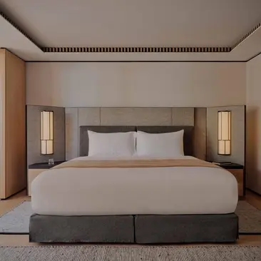 Deluxe bedroom with bed and wall-mounted lighting at Aman Rosa Alpina resort.