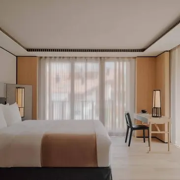 Deluxe Suite with village views at Aman Rosa Alpina resort, featuring a bed, seating area and floor-to-ceiling windows.
