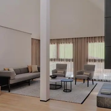 Dolomites Suite at Aman Rosa Alpina resort, showing seating area with sofa, armchairs and large windows with curtains.