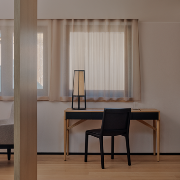 Dolomites Suite workspace at Aman Rosa Alpina with desk, chair and mountain views through sheer curtains.