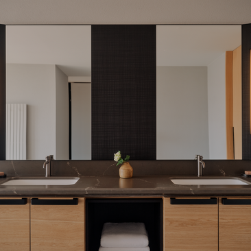 Bathroom at Aman Rosa Alpina with dual wooden vanities, dark central panel and large mirror.