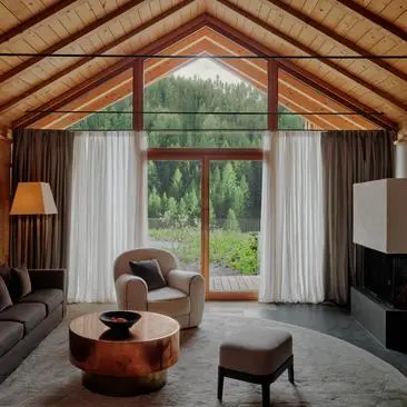 Zeno Suite at Aman Rosa Alpina resort, with soaring timber ceilings, arched windows framing Alpine views, and warm furnishings.