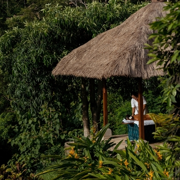 Outdoor spa treatment pavilion with thatch roof at Amandari resort, Bali, surrounded by lush greenery.