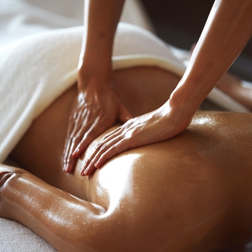 Therapist's hands applying warm oil during a traditional massage treatment at Amanjiwo.