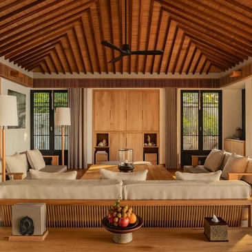 Living room at Amanoi with wooden ceiling, seating areas, and ocean views through large windows.