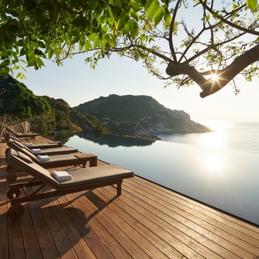 Wooden deck with loungers overlooking calm waters and forested coastline at Amanoi, Vietnam.