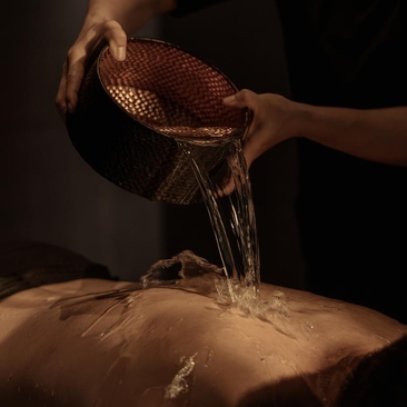 Water being poured from a copper vessel onto stone at Amanyangyun's spa and wellness hammam in China.