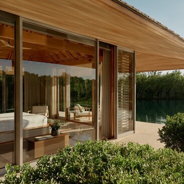 Wooden pavilion at Amanyara with sliding doors opening to terrace and gardens beyond.