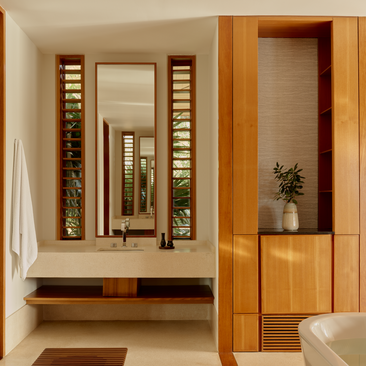 Bathroom at Amanyara with wooden vanity, illuminated mirror and teak accents.