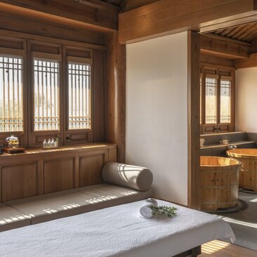 Spa treatment room at Amandayan with wooden screens, massage bed, and stone accents.