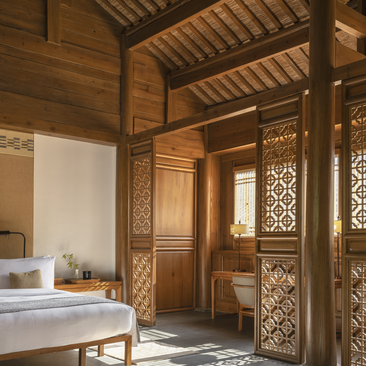 Courtyard Suite bedroom at Amandayan with carved wooden doors, platform bed, and latticed screens filtering natural light.