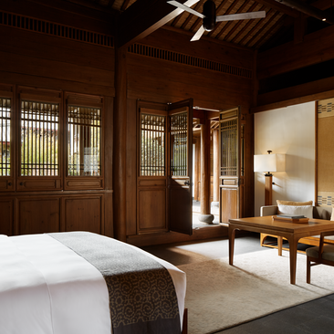 Courtyard Suite bedroom at Amandayan with wooden latticed doors, traditional furnishings, and serene earth tones.