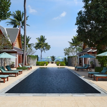 Pathway leading to the ocean at Amanpuri resort in Thailand, flanked by palm trees and open-sided pavilions.