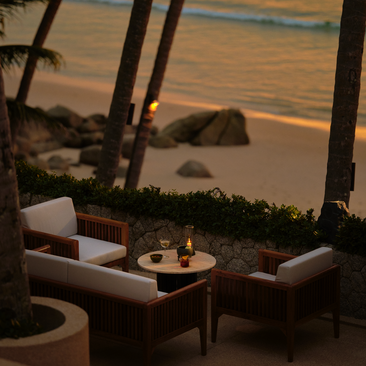 Sunset Terrace at Amanpuri resort with cocktails and seating overlooking golden coastal waters at dusk.