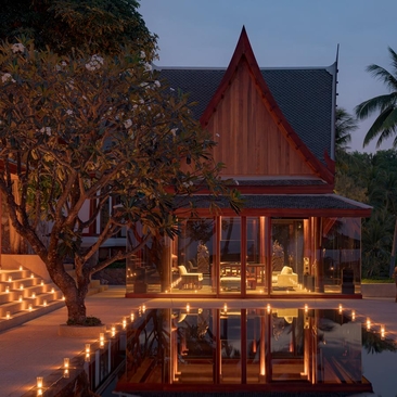 Eight-bedroom ocean villa with outdoor pool and pavilion at Amanpuri, Thailand, illuminated at dusk.