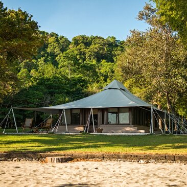 Ocean view tent accommodation at Amanwana, set on sandy beach with tropical woodland beyond.