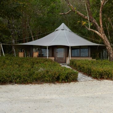 Ocean View Tent at Amanwana, Indonesia, with canvas structure and wooden details amid tropical vegetation.