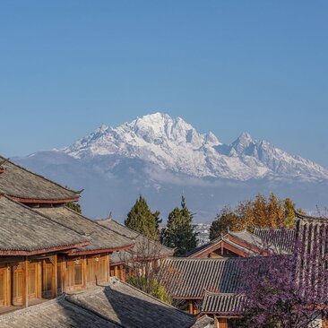 Snow-capped mountain rising behind traditional wooden buildings at Amandayan resort in spring.