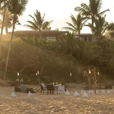 Couple dining at a candlelit table on the beach at Amanera resort, Dominican Republic.