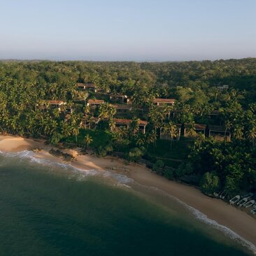 Aerial view of Amanwella's beachfront suites set amongst dense tropical forest along a quiet sandy cove.