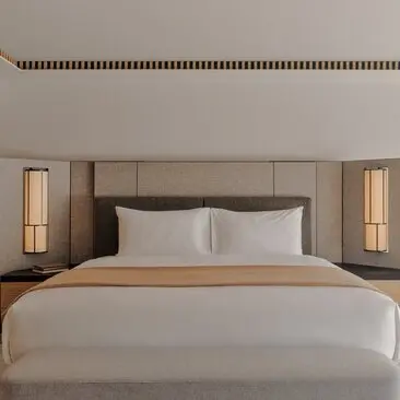 Rosa Alpina room with bed, neutral tones and paired wall lights at Aman Rosa Alpina resort.