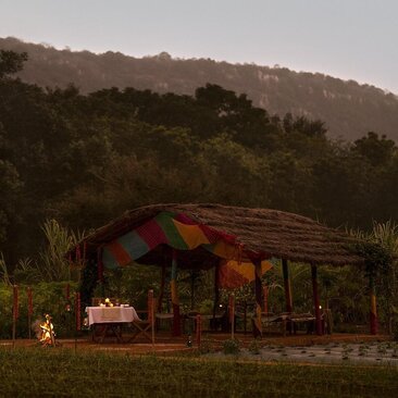 Candlelit dining tent at Aman-i-Khas with organic farm views at dusk, India.