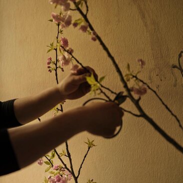 Masterclass di Ikebana presso Aman New York, hands arranging branches and flowers.