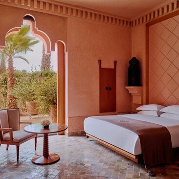 Grand Two-Bedroom Pool Villa principal bedroom at Amanjena resort, Morocco, with terracotta walls and arched windows.
