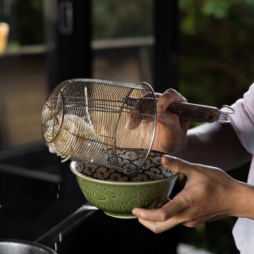 Chef holding a woven basket of fresh herbs at Amanoi's cooking class in Vietnam.