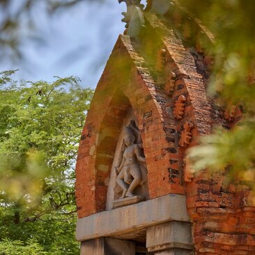 Ancient brick tower of the Cham Kingdom partially obscured by verdant foliage at Amanoi, Vietnam.