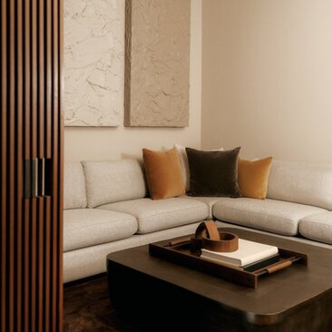 Sala cinematografica della residenza con tre camere da letto ad Aman New York, con divano angolare beige e tavolino nero.