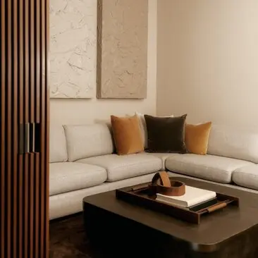 Movie room seating area at Aman New York with curved sofa, decorative pillows, and wooden screen divider.