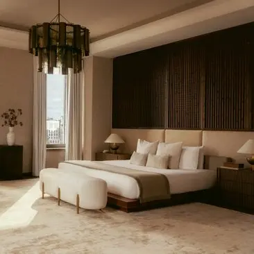 Three-bedroom penthouse principal bedroom at Aman New York with dark wood paneling, brass pendant light, and neutral furnishings.