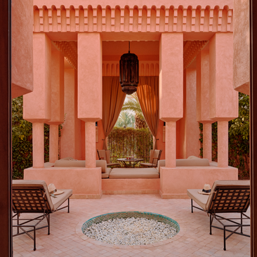 Moroccan pavilion at Amanjena resort featuring terracotta columns, central fountain and striped seating chairs.