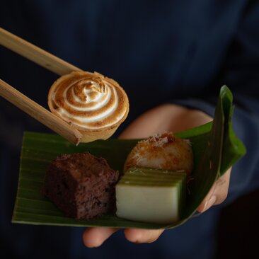 Balinese afternoon tea service at Amankila resort, featuring pastries and tea on a green leaf-shaped plate.