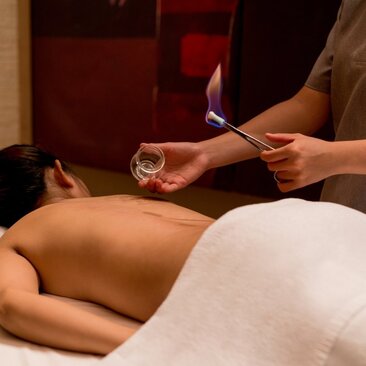 Therapist pouring warm oil onto guest's back during Vietnamese massage at Amanoi spa.