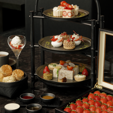 Tiered stand displaying strawberry afternoon tea at Aman Tokyo, featuring pastries, scones and fresh berries on three levels.