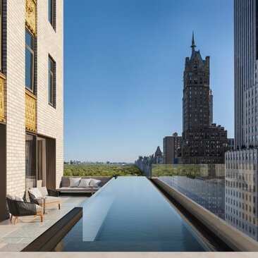 Reflecting pool at Aman New York with Chrysler Building view and terrace seating.
