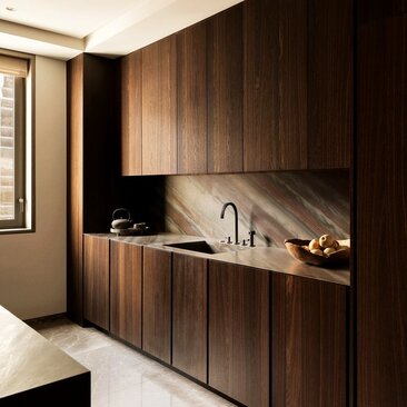 Cucina con armadi in legno scuro nell'appartamento con tre camere da letto all'Aman New York.