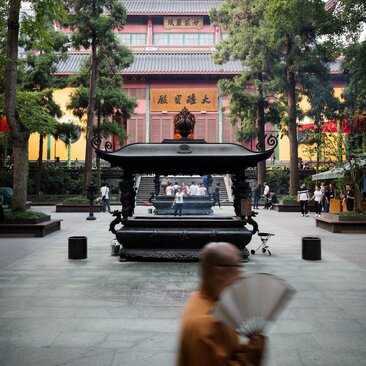 法云安缦度假村内，僧侣在庭院中行走，背景为灵隐寺古建筑。