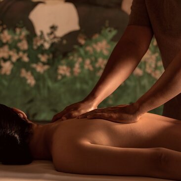 Therapist's hands performing a back massage on a guest at Amanoi's spa treatment room.