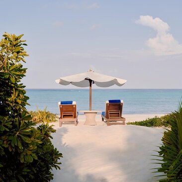 Grand Beach Pool Casita at Amanpulo: two loungers and parasol facing turquoise waters, Philippines.