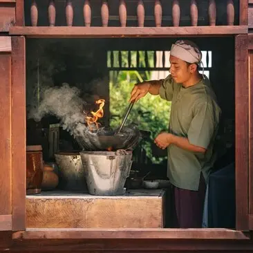 Khmer village kitchen at Amansara with chef cooking over traditional fire and fresh herbs.